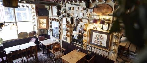 A room with wooden furniture, a patterned rug, and various framed items on the walls.