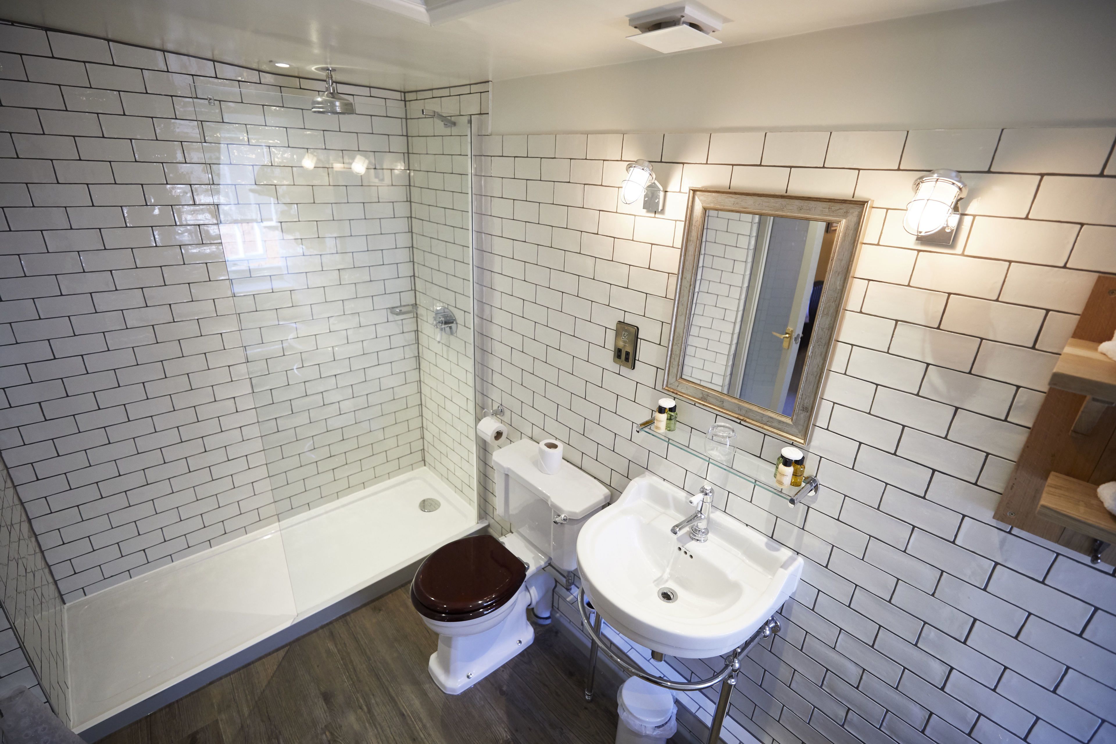 A bathroom with a glass-enclosed shower, a white toilet, and a white sink with a mirror above it.