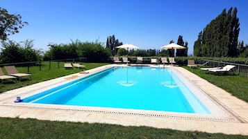 Una piscina al aire libre de temporada, sombrillas