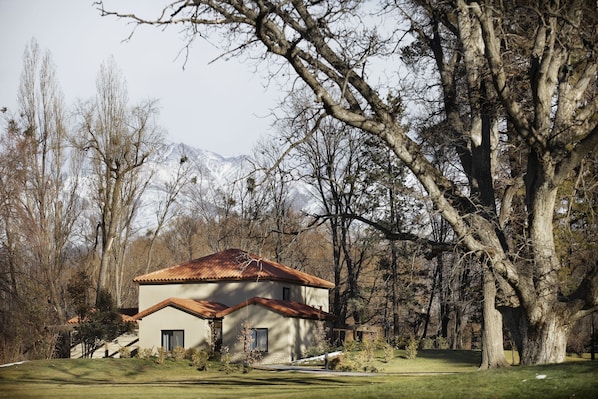 A house with a sloped roof, surrounded by trees and a mountain in the background.