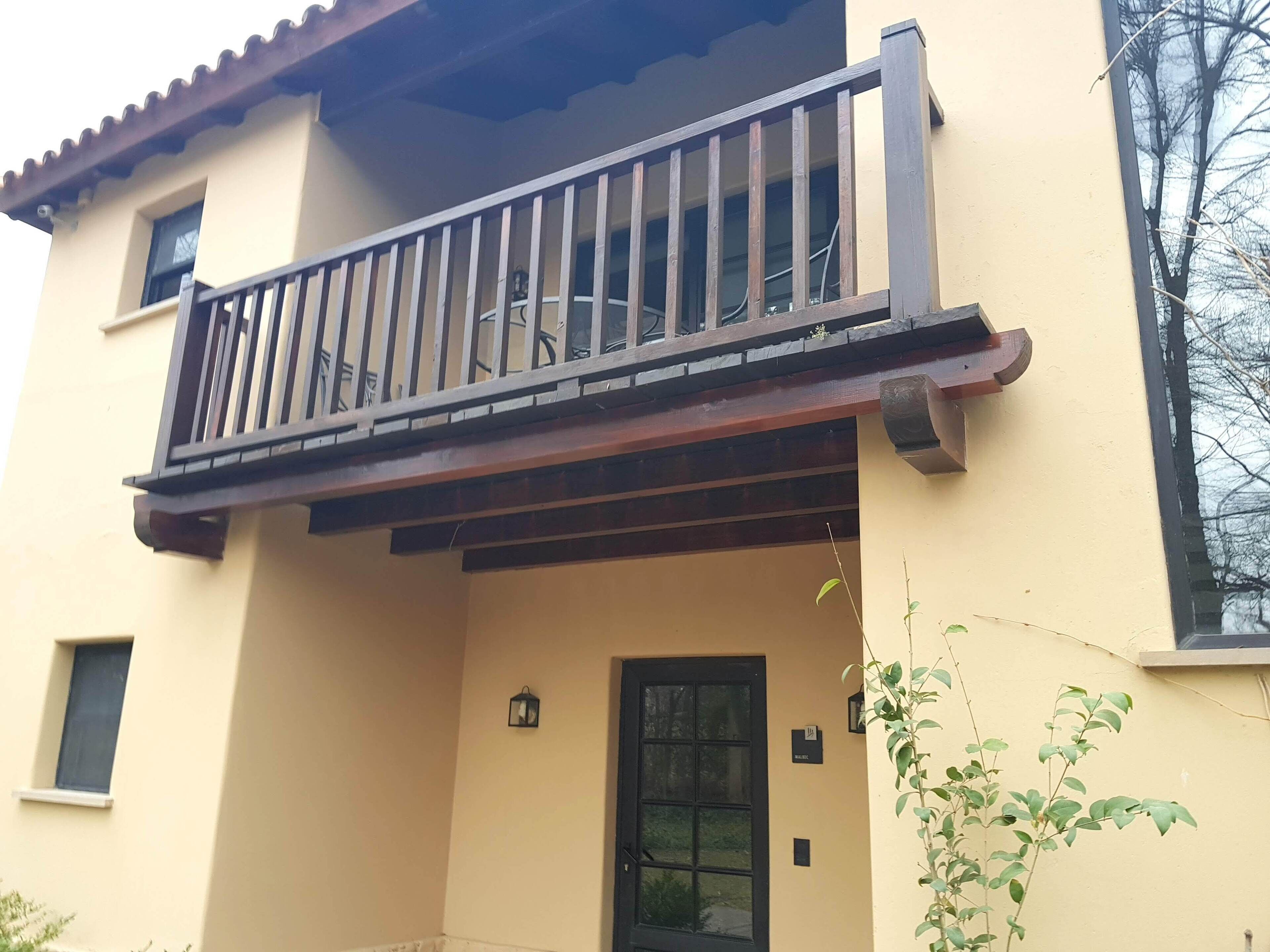 A building with a balcony, a door, and a small window.