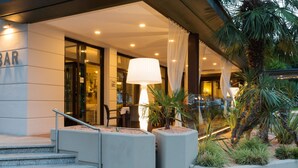 Entrada de un hotel con un letrero de bar, una escalera y una lámpara grande.