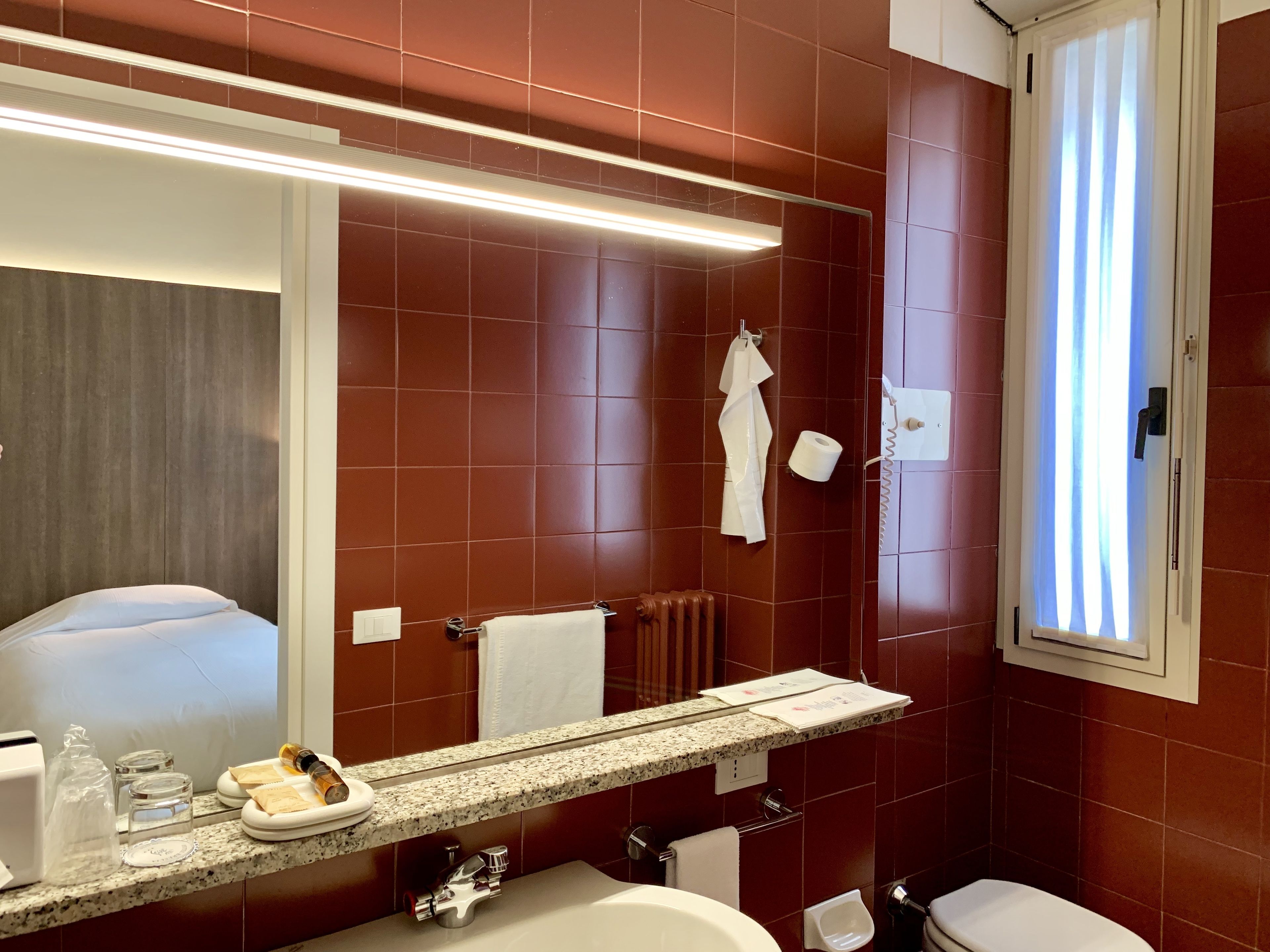 A modern bathroom with a large mirror, a sink, a toilet, and a shower area.