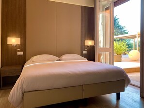Een slaapkamer met een groot bed, nachtlampen, een nachtkastje en uitzicht op de omgeving.