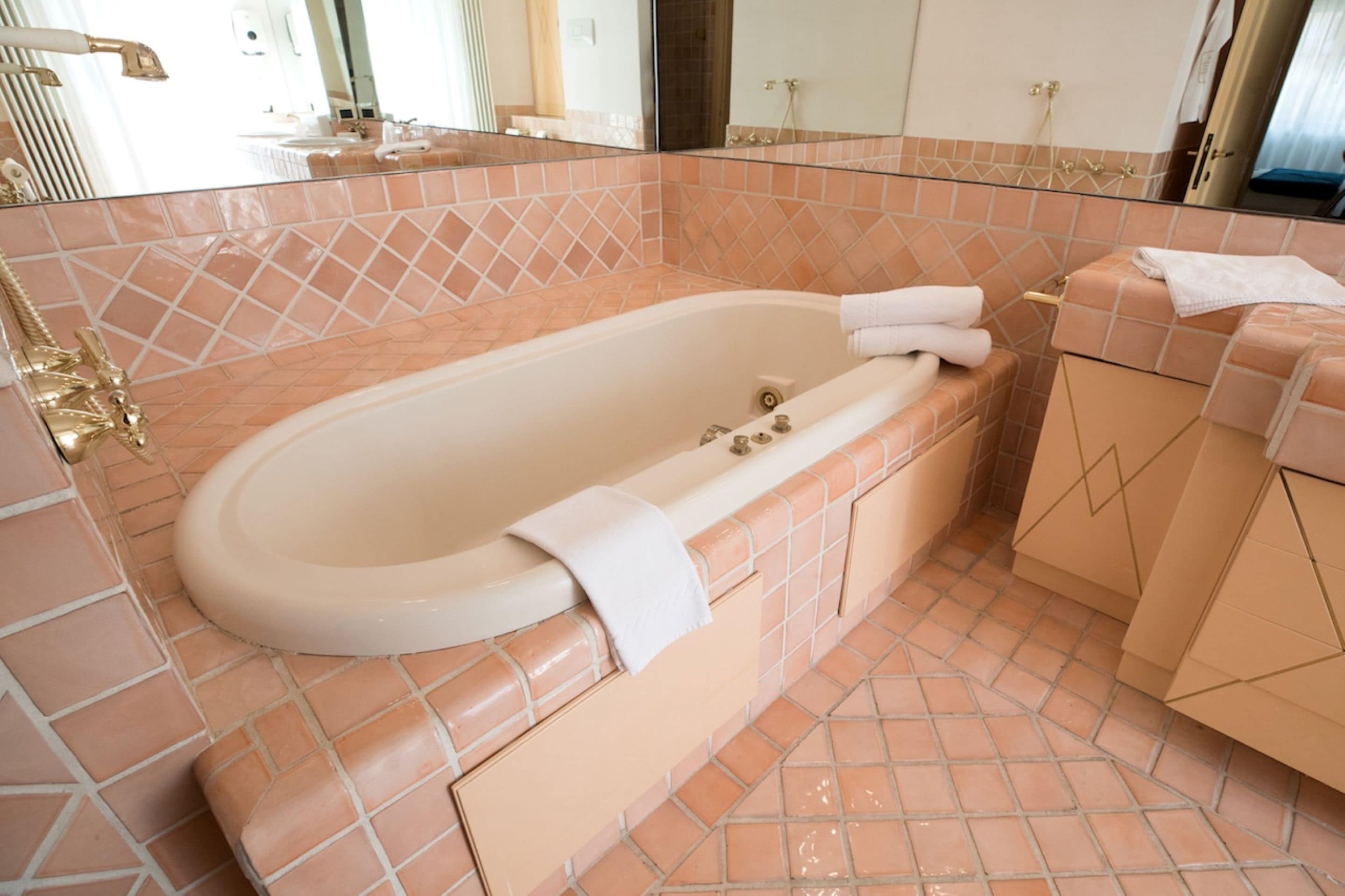 Une salle de bain avec une baignoire sur pieds, un meuble-lavabo avec un miroir et un porte-serviettes.