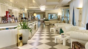 Un vestíbulo de hotel con piso a cuadros, una zona de bar con varias botellas y asientos confortables.
