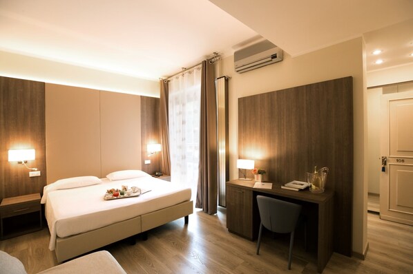 A hotel room with a bed, desk, chair, and bedside lamps.