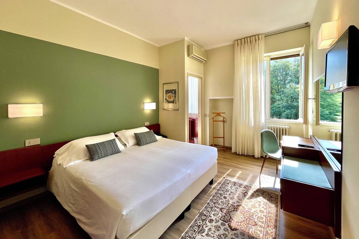 Een hotelkamer met een groot bed, een bureau, een stoel en een televisie.