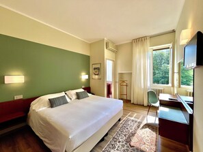 Une chambre d’hôtel avec un grand lit, un bureau, une chaise et un téléviseur.