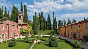 Un patio con una torre de reloj, jardines cuidados y arquitectura tradicional.