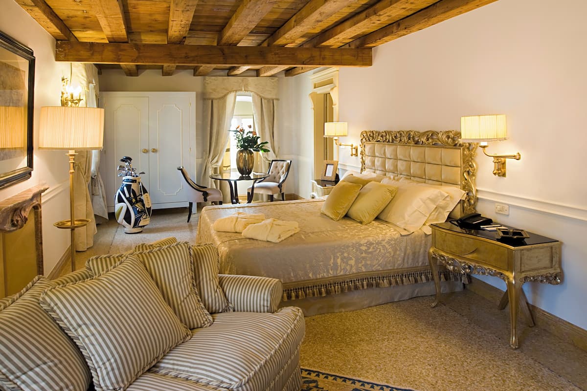 A bedroom with a large bed, a sofa, a small table, and a chair.
