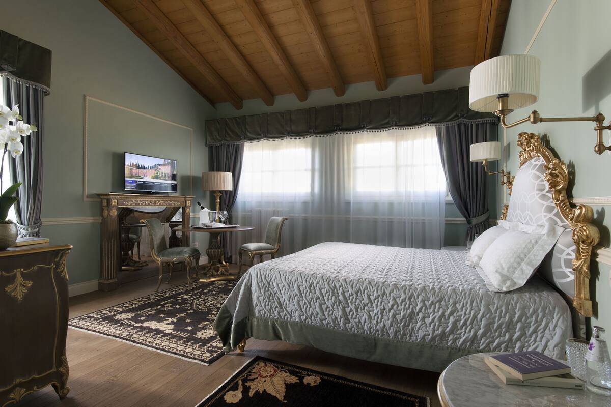 A bedroom with a bed, desk, chairs, and a television.