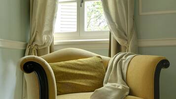 A room with a window, a chair, and a wall-mounted light fixture.