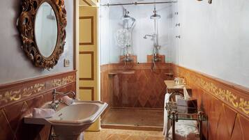 Une salle de bain dotée d’une commode d’époque, d’un lavabo sur pied, d’une douche à parois de verre et d’un miroir décoratif.