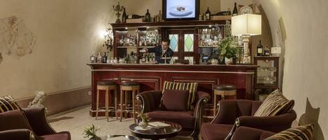 A bar area with a television, shelves with bottles, and a seating area with chairs and a sofa.