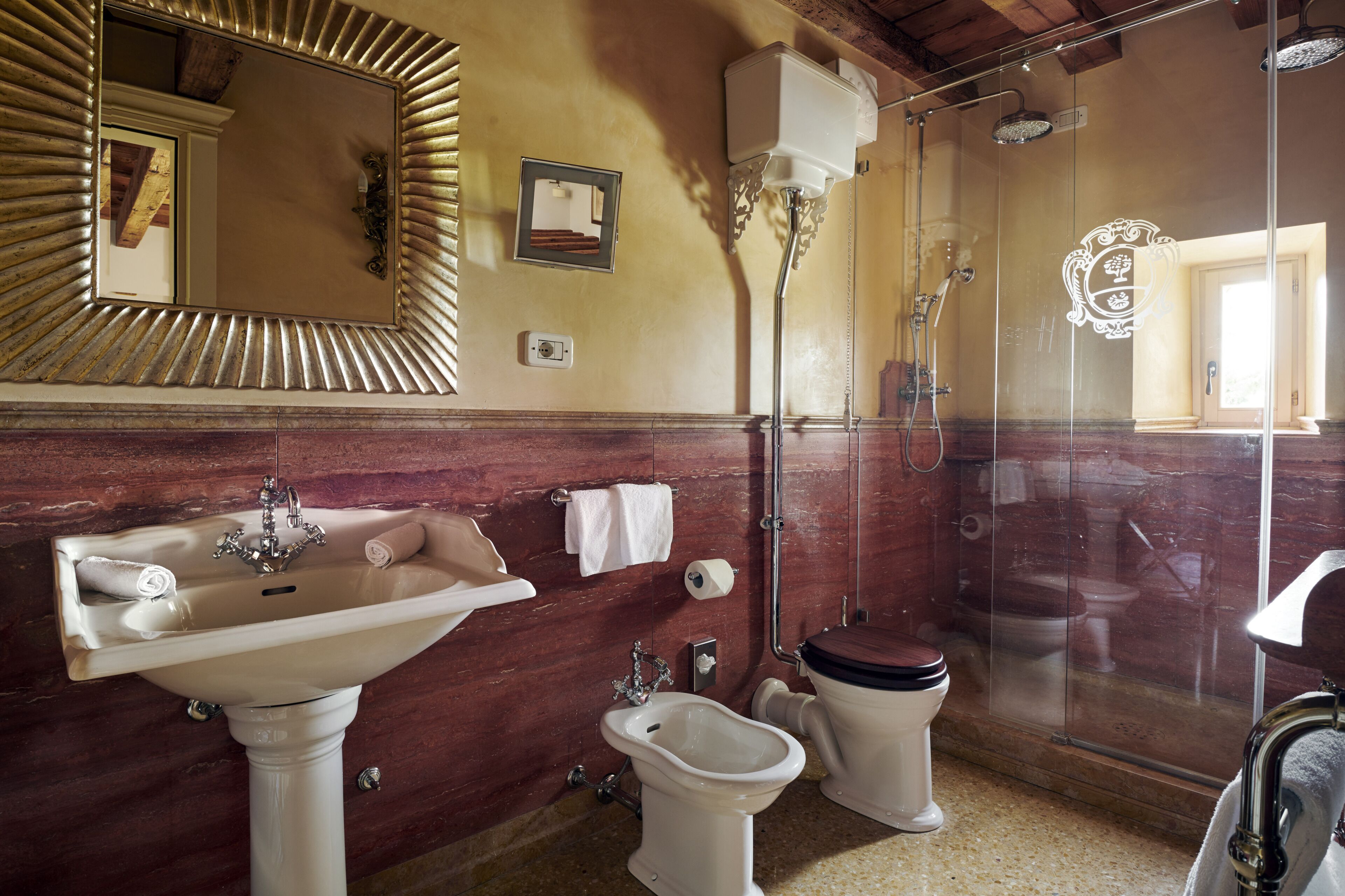 Un baño con lavamanos, inodoro, bidé y cabina de ducha con mampara de vidrio.