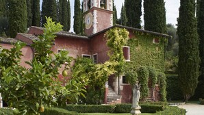 A pink building with a clock tower, surrounded by well-manicured hedges and tall cypress trees. - Villa Cordevigo  (Cavaion Veronese)