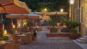 An outdoor patio with tables and chairs, covered by umbrellas, and a stone staircase leading to a higher level. - Villa Cordevigo  (Cavaion Veronese)