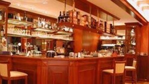 Una zona de bar con mostradores y taburetes de madera.