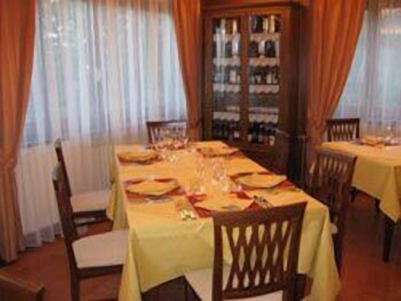 A dining area with a long table set for four, surrounded by wooden chairs.