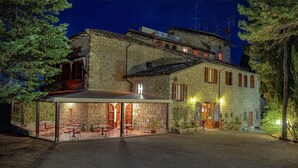 Un edificio de piedra con un área de estar al aire libre techada y una entrada bien iluminada.