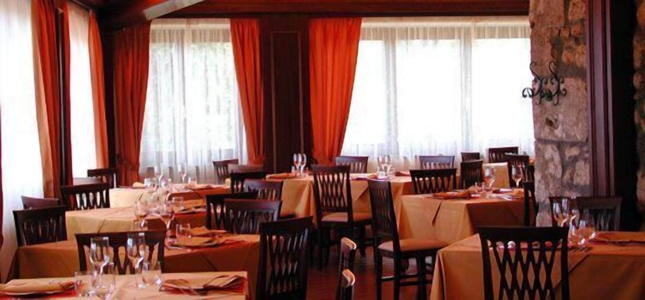 A restaurant with multiple tables and chairs, each set with wine glasses and cutlery.