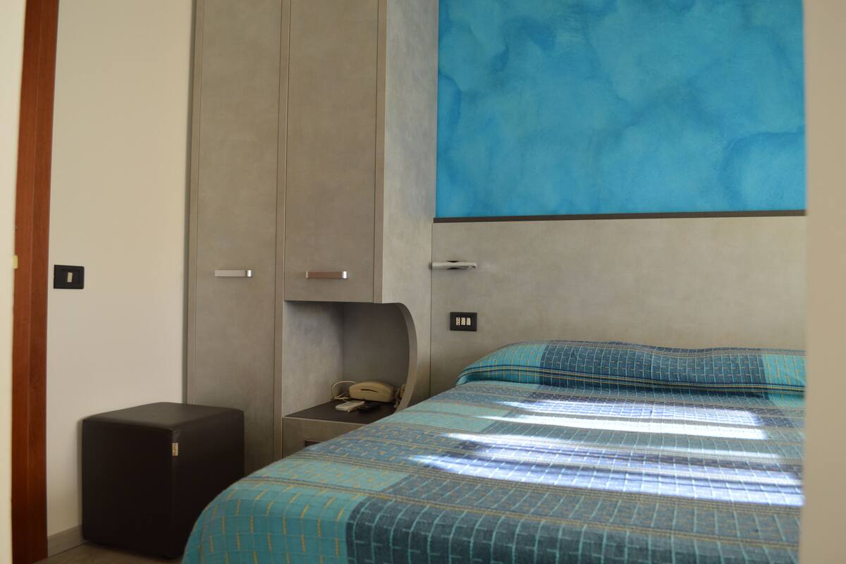 Un dormitorio con cama, mesita de noche, teléfono y armario.
