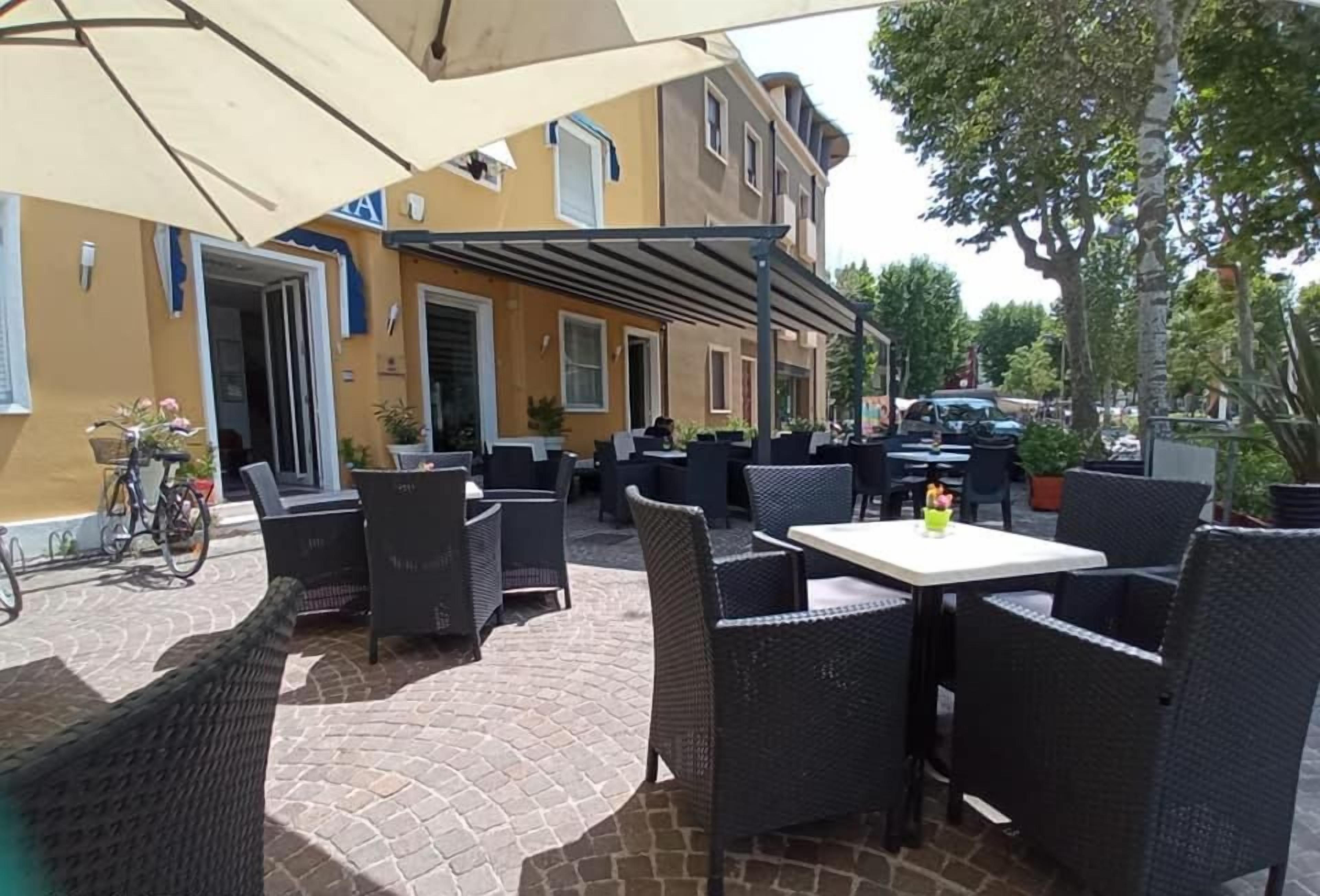 An outdoor patio area with wicker furniture, a table, and a bicycle parked outside a building.