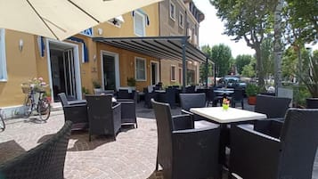 An outdoor patio area with wicker furniture, a table, and a bicycle parked outside a building.