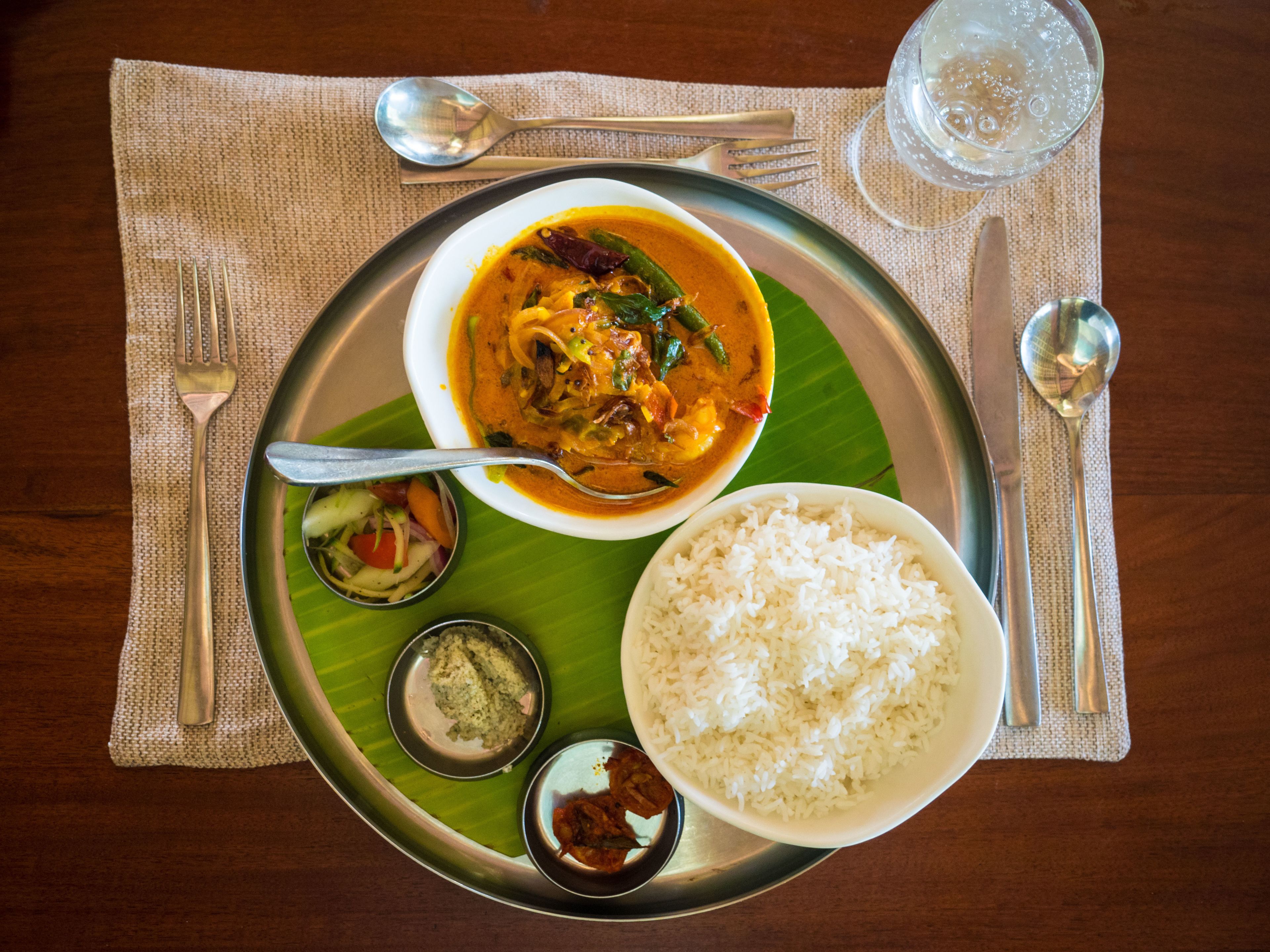 Un repas composé de riz, de curry et d’accompagnements, servi dans une assiette en métal.