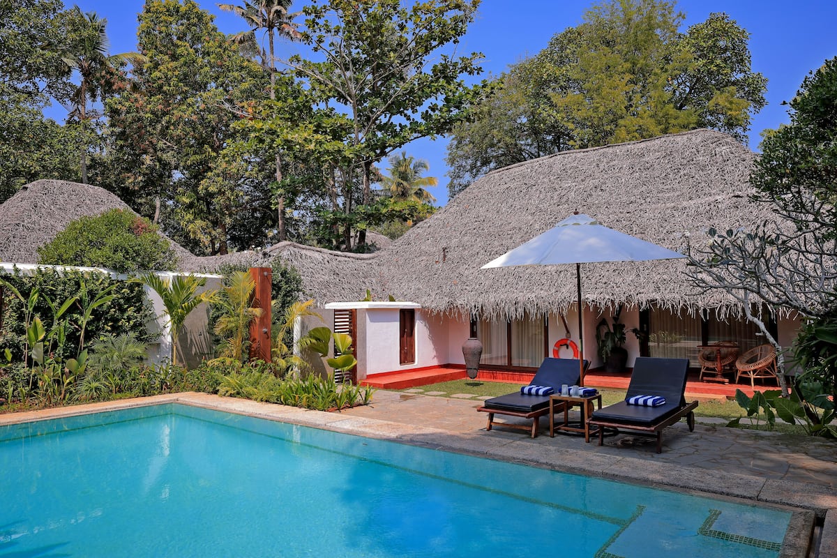 A pool area with lounge chairs and a thatched-roof structure.