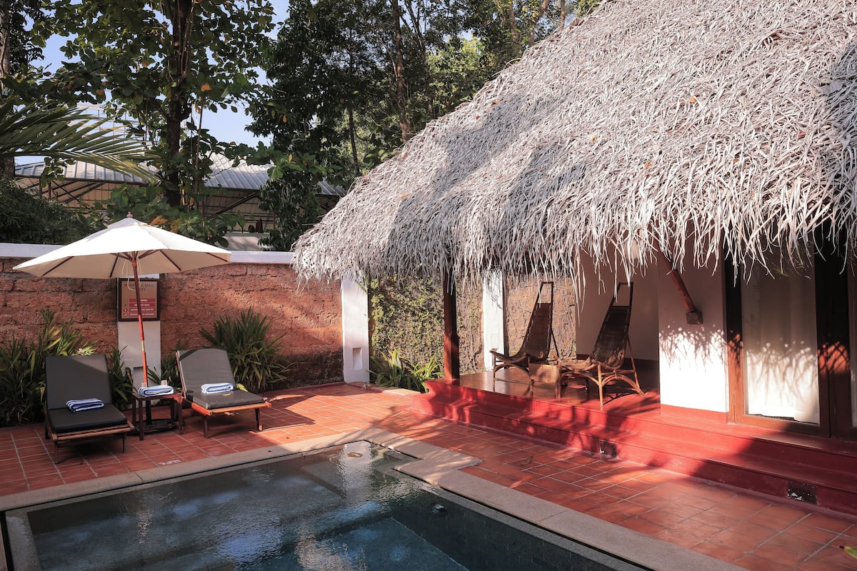 A pool area with lounge chairs and a thatched-roof structure.