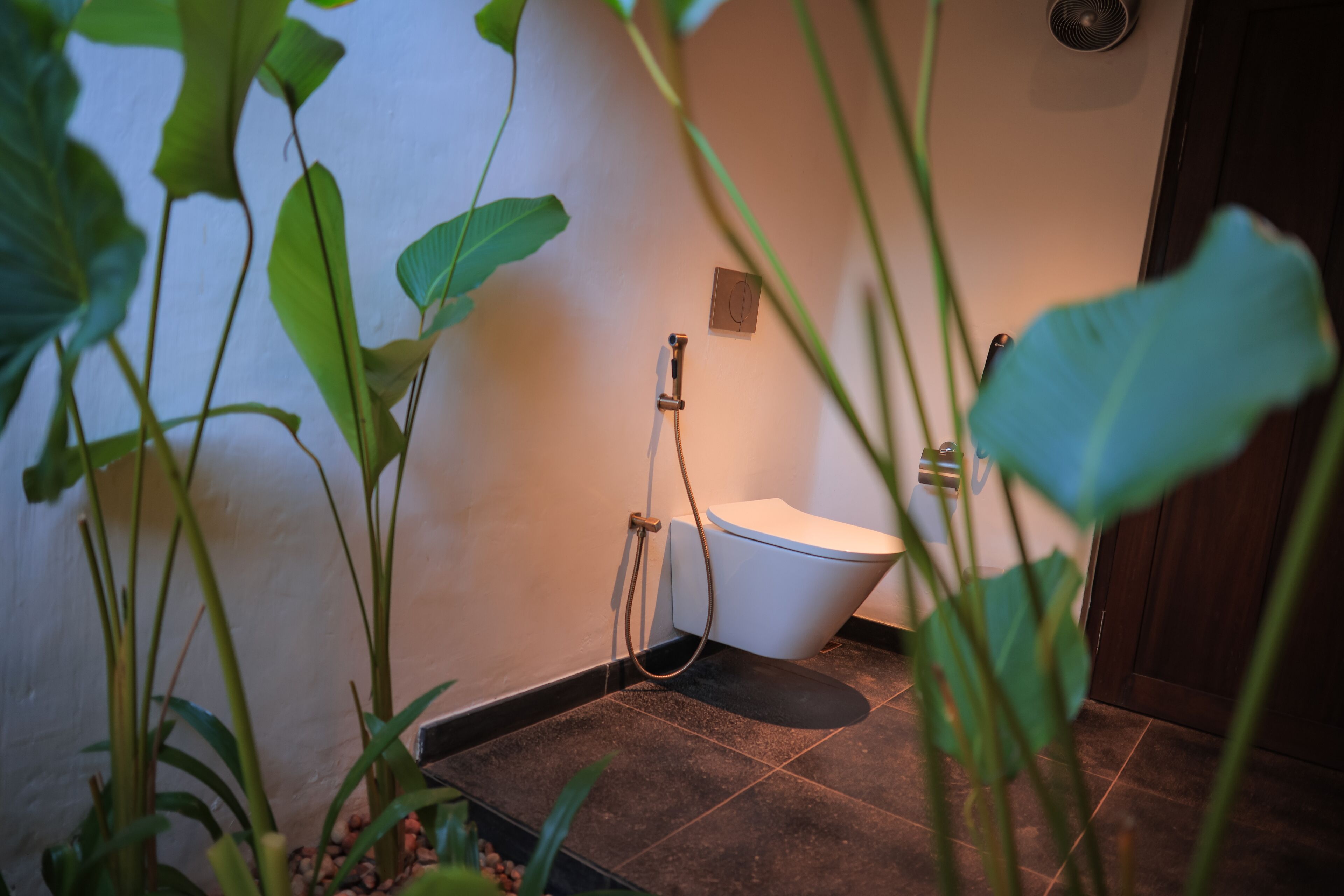 A bathroom with a toilet, shower, and a small sink.