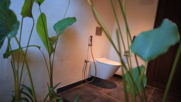 Une salle de bain avec des toilettes, une douche et un petit lavabo.