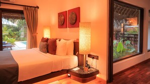 Quarto de hotel com uma cama grande, uma mesa de cabeceira com abajur, uma janela com vista para o exterior e duas obras de arte penduradas na parede.