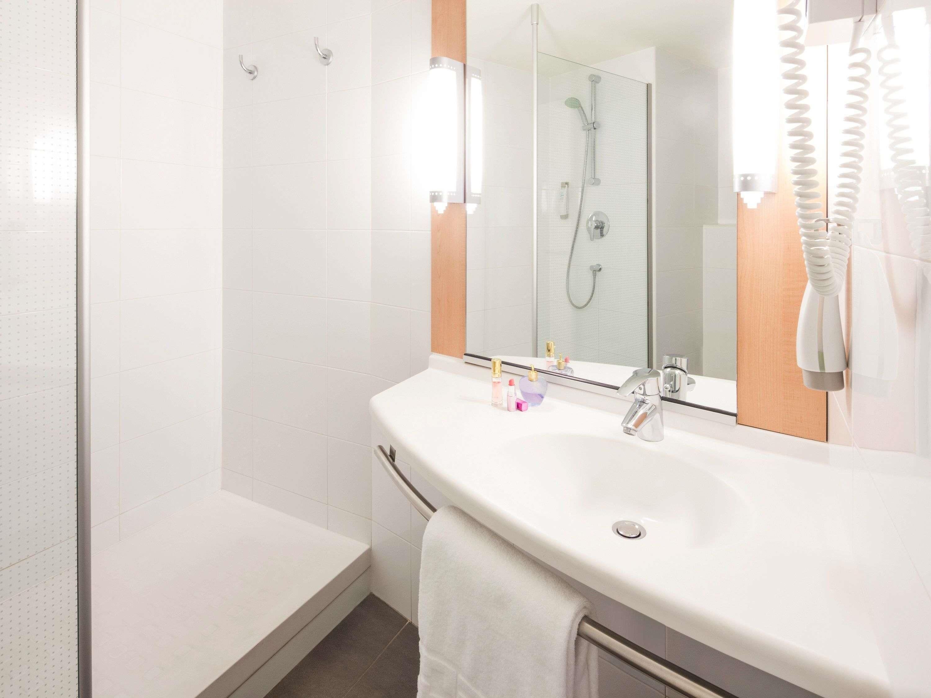 A bathroom with a white sink, mirror, and shower.