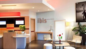 A hotel reception area with a modern design, including a reception desk, seating area, and a wall-mounted sign for 'ibis Santa Coloma'. - ibis Barcelona Santa Coloma (Santa Coloma de Gramenet)
