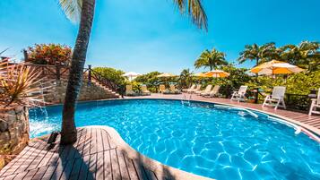 Una piscina al aire libre, sombrillas, sillones reclinables de piscina