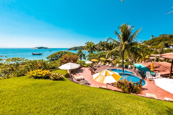 Una piscina al aire libre, sombrillas, sillones reclinables de piscina