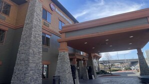 A hotel with a stone facade, a covered entrance, and a clear sky. - Best Western Plus KC Speedway Inn & Suites (Kansas City)