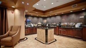 A hotel lobby with a central coffee station, a seating area, and a patterned wall. - Best Western Plus KC Speedway Inn & Suites (Kansas City)