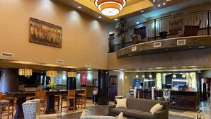 A spacious lobby with a central seating area, a bar, and a staircase leading to an upper level. - Best Western Plus KC Speedway Inn & Suites (Kansas City)