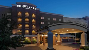 Un hotel Courtyard by Marriott con entrada cubierta, fachada de ladrillo y múltiples ventanas.