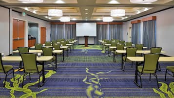 Una sala conferenze con file di sedie, uno schermo per proiezioni e un podio.