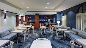 Um saguão de hotel com áreas de estar, um bar e uma mesa de recepção.