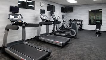 Ein Fitnessstudio mit Laufbändern, Crosstrainern und Gewichtbänken.