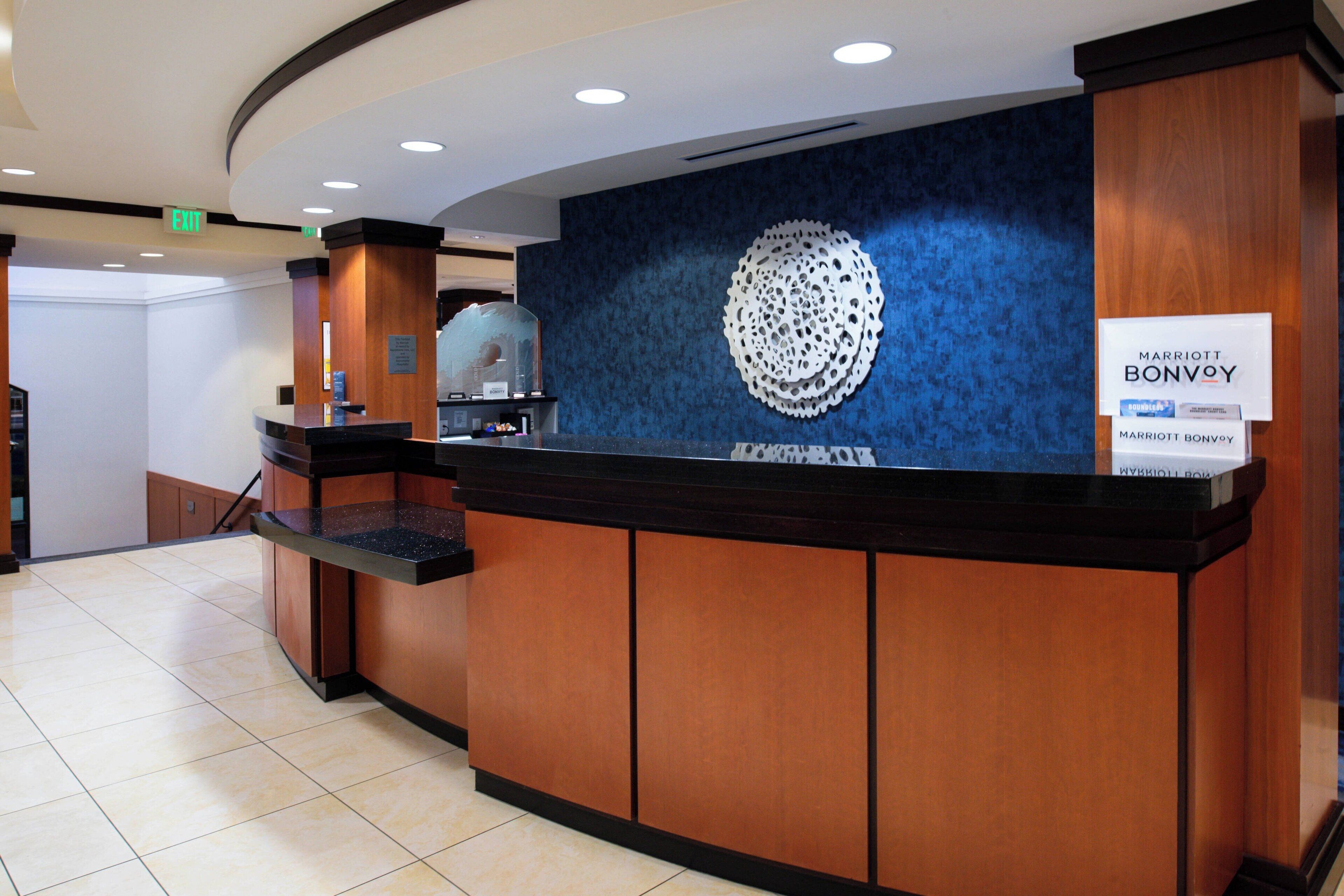 A reception desk with a blue wall and a circular design, a sign for Marriott Bonvoy, and a tiled floor.
