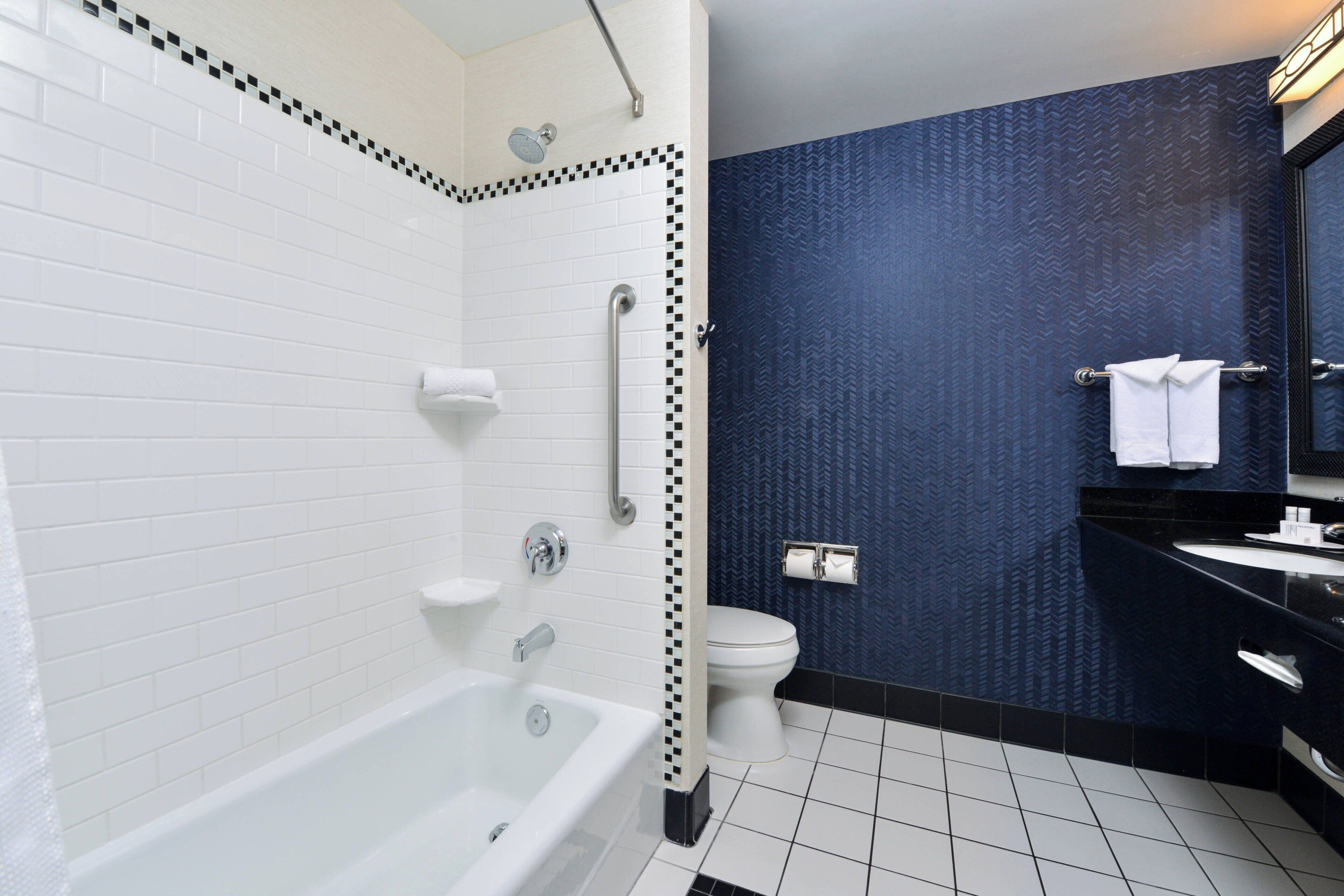 A modern bathroom with a white bathtub, a toilet, and a sink.