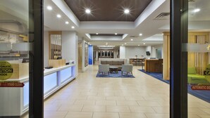 A hotel lobby with a reception desk, seating area, and a staircase leading to upper floors. - Holiday Inn Express Hotel & Suites Niles by IHG (Niles)