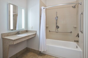 Een badkamer met een wastafel, spiegel, douche en bad.